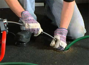 a Salinas drain clearing specialist is using a snake to clear the drain